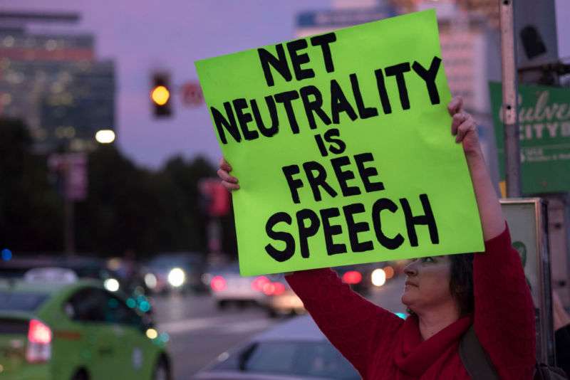 A woman outside a federal building in Los Angeles holds a sign reading, 