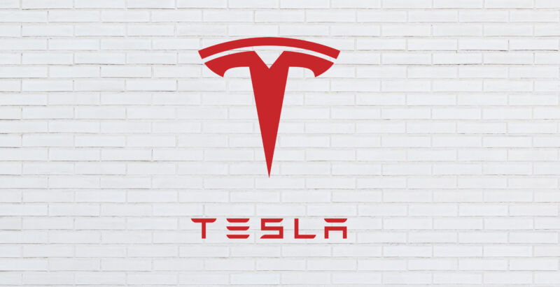 The Telsa logo superimposed on top of a white brick wall